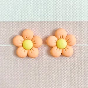 Detailed view of matte resin orange five-petal flower charms with yellow stamen centers