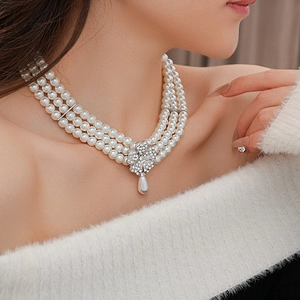 Close-up of triple-layer pearl necklace featuring a floral rhinestone drop pendant