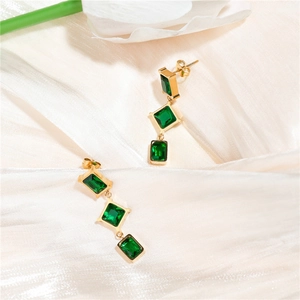 Detail of emerald green geometric drop earrings with triple stones on silk fabric