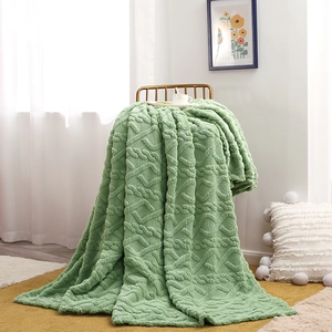 Sage green fleece blanket with cable knit texture draped over a chair in a cozy room