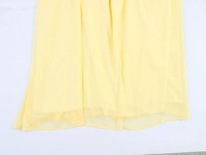 Détail de l'ourlet de la robe bohème en mousseline jaune montrant la texture légère et fluide
