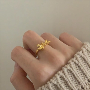Close-up of golden bow ring for women worn on a finger for an elegant, warm aesthetic