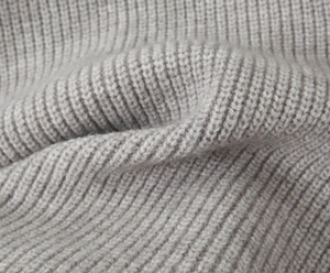Macro shot of gray rib-knit fabric texture showing detailed yarn and thick weave