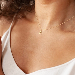 Close-up of a gold initial A pendant necklace worn on a neck for a stylish look