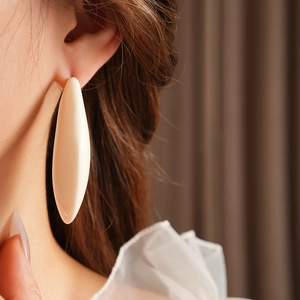 Gros plan d'une boucle d'oreille goutte en résine crème pour un style minimaliste