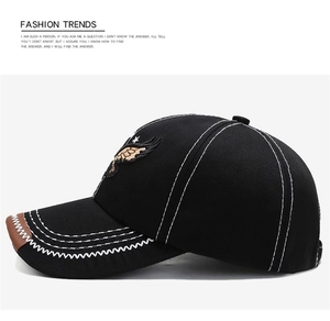 Detail of black baseball cap with golden eagle embroidery and contrast white stitching