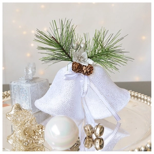 Close-up of velvet white Christmas bells with pine needles and pinecone on a silver tray