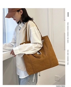 Detail shot of brown corduroy tote bag showing ribbed texture and white logo label