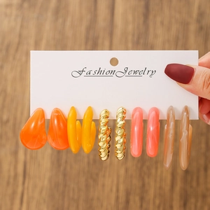 Detailed close-up of 5 pairs of colorful acrylic and metal hoop earrings on display card