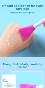 Detailed view of pink silicone spatula brush applying a mud mask evenly on skin surface
