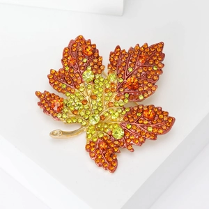 Macro shot of maple leaf brooch with vibrant orange and red rhinestone gradients