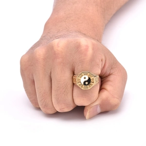 Close-up of gold stainless steel Tai Chi Yin Yang ring worn on a man's clenched fist