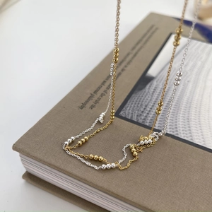 Close-up of minimalist gold and silver beaded necklaces on a vintage book