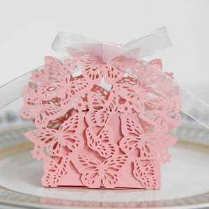 Macro detail of pink laser-cut butterfly candy box with a white ribbon on a plate