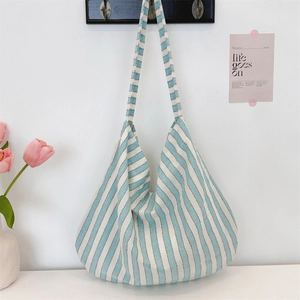 Vertical blue and white striped canvas tote bag hanging in a minimalist home setting