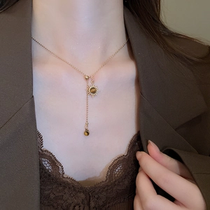 Détail du collier pendentif tournesol en œil de tigre sur une chaîne dorée porté par un mannequin