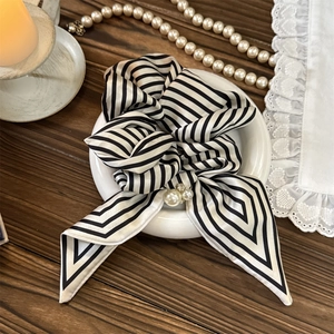Detail of black and white striped scrunchie with pearl accent and elegant bow design