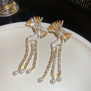 Macro detail of bowknot pearl tassel earrings with zircons on a ceramic tray