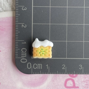 Close-up of a mini resin toast food charm on a measurement grid for DIY hair accessories