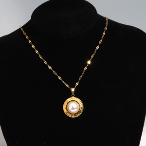 Close-up of golden shell flower pendant with pearl inlay on a black velvet necklace display