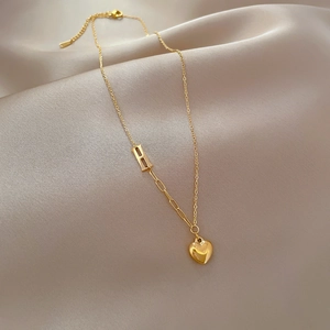 Detail of gold heart pendant necklace with letter R charm on silk fabric texture