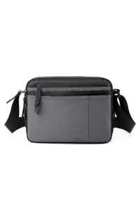 Detail of gray nylon crossbody bag showing multiple zipper pockets and logo branding