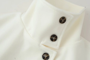 Close-up of white wool coat collar with three amber tortoise shell buttons detail