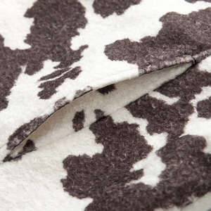 Close-up of fluffy black and white cow print fabric with functional side pocket detail