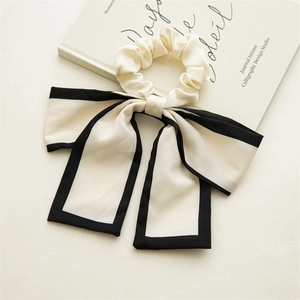 Detail of elegant beige satin bow hair scrunchie with black trim on a vintage book