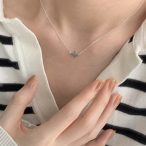 Close-up of minimalist S925 sterling silver bird pendant necklace on model's collarbone