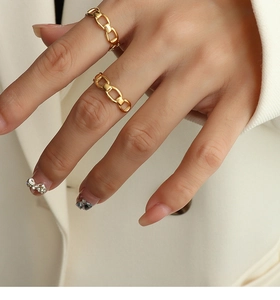 Detail shot of gold chain-link style layered rings on model's hand for chic daily wear
