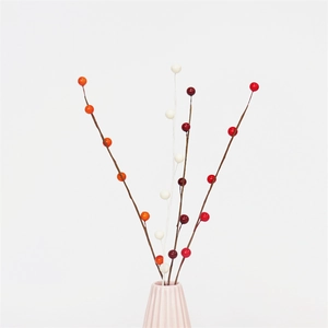 Colorful artificial berry branches in pink ceramic vase for festive home decoration