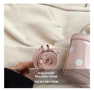Detail shot of the adjustable leather shoulder strap on a pink polka dot bucket bag