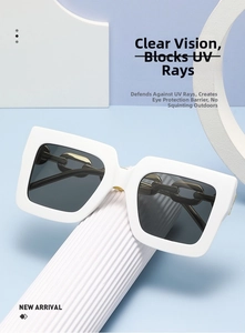 Detalle de gafas de sol cuadradas blancas con diseño de cadena dorada en las patillas