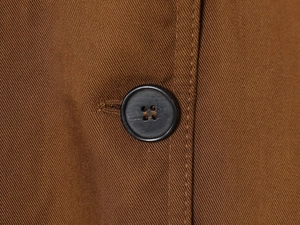 Detail of dark brown twill fabric texture and a black four-hole button on the jacket