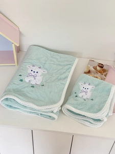 Detail of soft mint green coral fleece towel set with cute lamb embroidery and braided edges