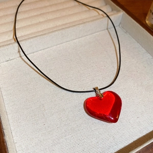 Gros plan du collier avec pendentif cœur en verre rouge dans un présentoir à bijoux