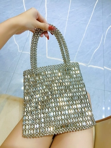 Close-up of a shimmering silver beaded handbag with metallic oval sequins and short handle