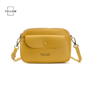 Detail of yellow crossbody bag featuring litchi texture and silver metal hardware