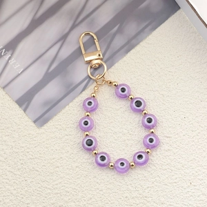 Detailed macro view of purple Evil Eye beads with golden lobster clasp and spacer beads