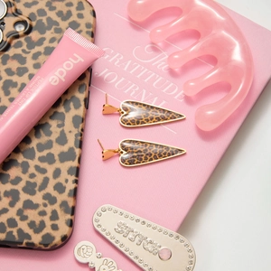 Detailed view of leopard print heart earrings on a pink aesthetic lifestyle background