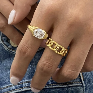 Gold-plated stainless steel chain ring and oval rhinestone set against blue denim fabric