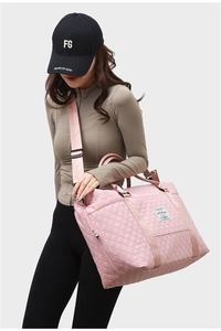 Pink quilted large fitness tote bag with crossbody strap shown being worn by a model