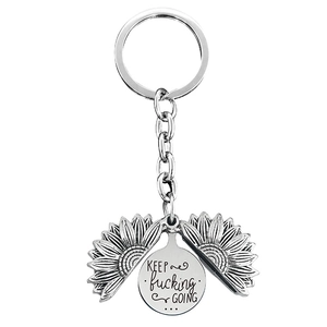 Detail of opening silver sunflower keychain with engraved Keep fucking Going message