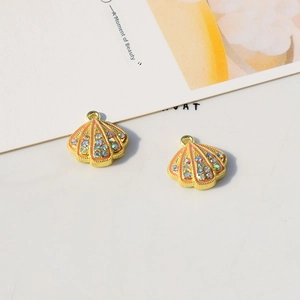 Macro detail of gold-plated starfish shell pendants with pink enamel and colorful rhinestones
