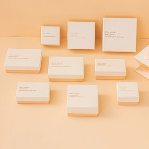 Various sizes of beige and orange jewelry gift boxes featuring elegant gold lettering