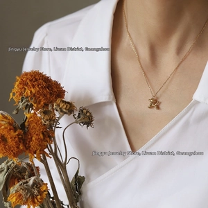 Close-up of a 18K gold plated balloon dog pendant necklace on a minimalist shirt