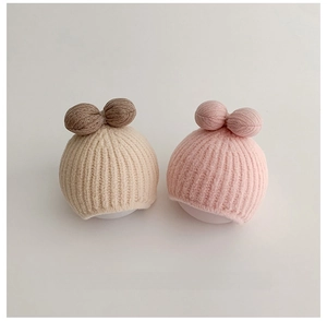 Detail of soft knit baby hats featuring vertical stripe texture and beige pink tones