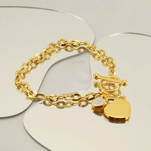 Golden double chain bracelet with heart pendants and T-bar clasp closure on a display