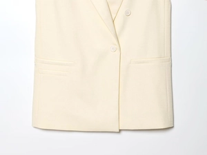 Vue macro détaillée du gilet ivoire montrant la texture sergé et le bouton blanc